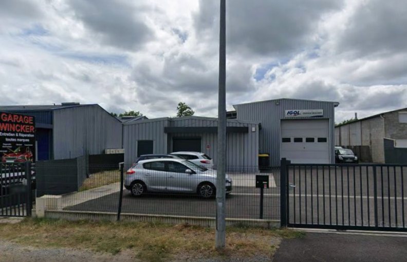 Entrée du Garage Wincker depuis la rue, avec l’enseigne « Entretien et réparation toutes marques »