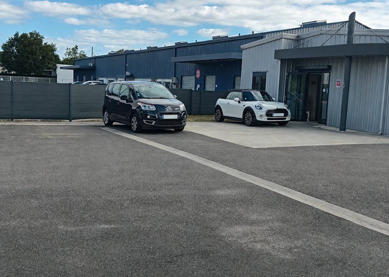 Accueil du Garage Wincker et parking clients, avec des véhicules stationnés devant l’entrée vitrée